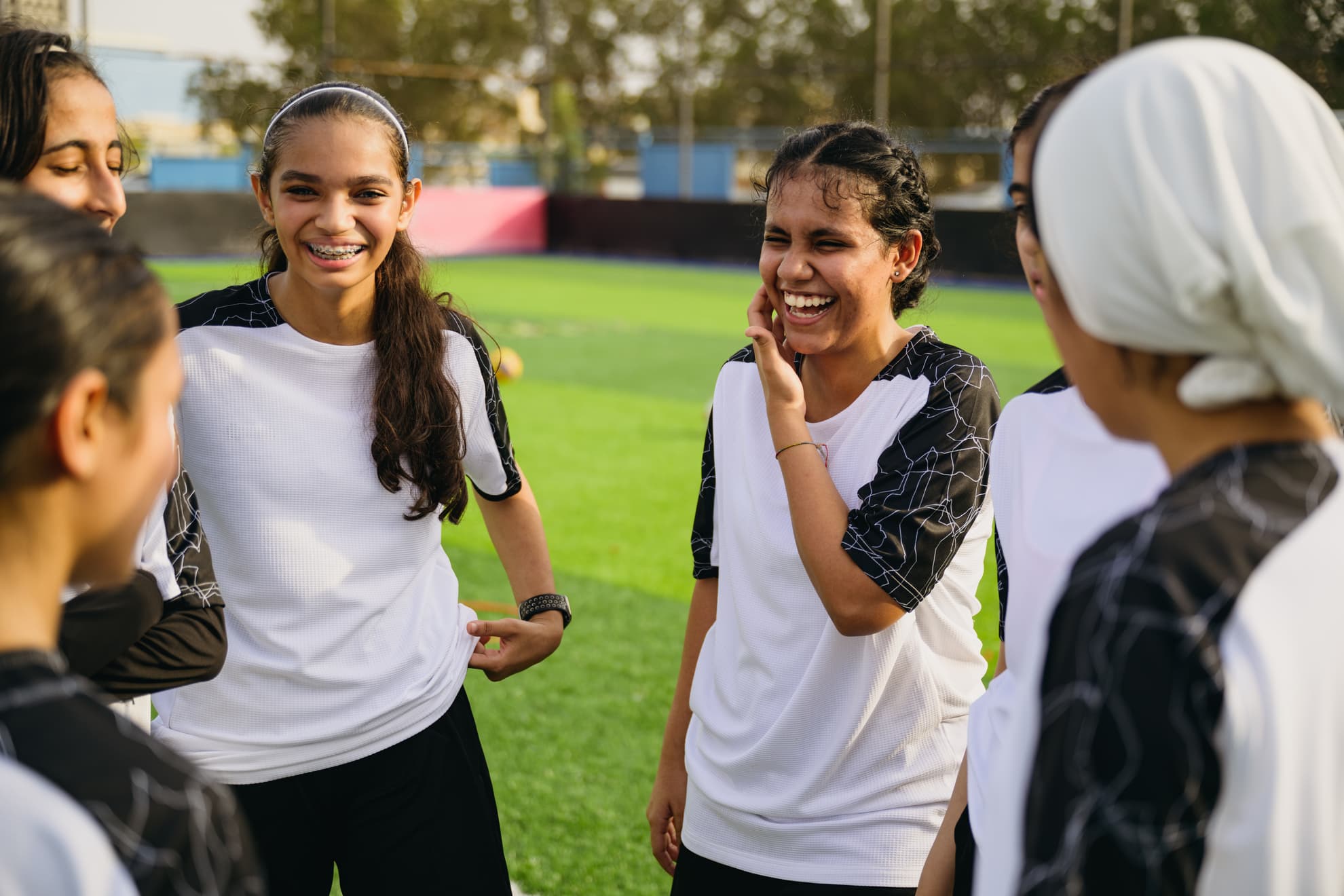 Cheerful soccer players talking at sports field.