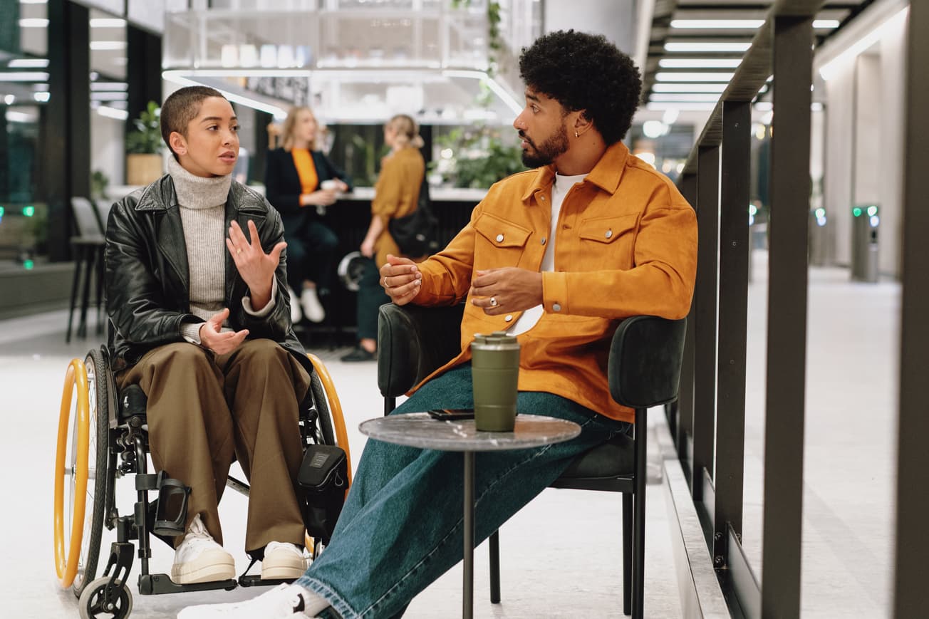 Two colleagues have animated chat in lobby area of modern office