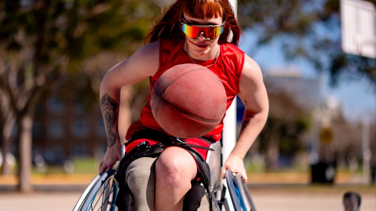 A woman playing basketball outside in a wheelchair.