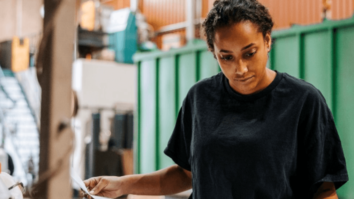 A person holding pen and paper working in a workshop.