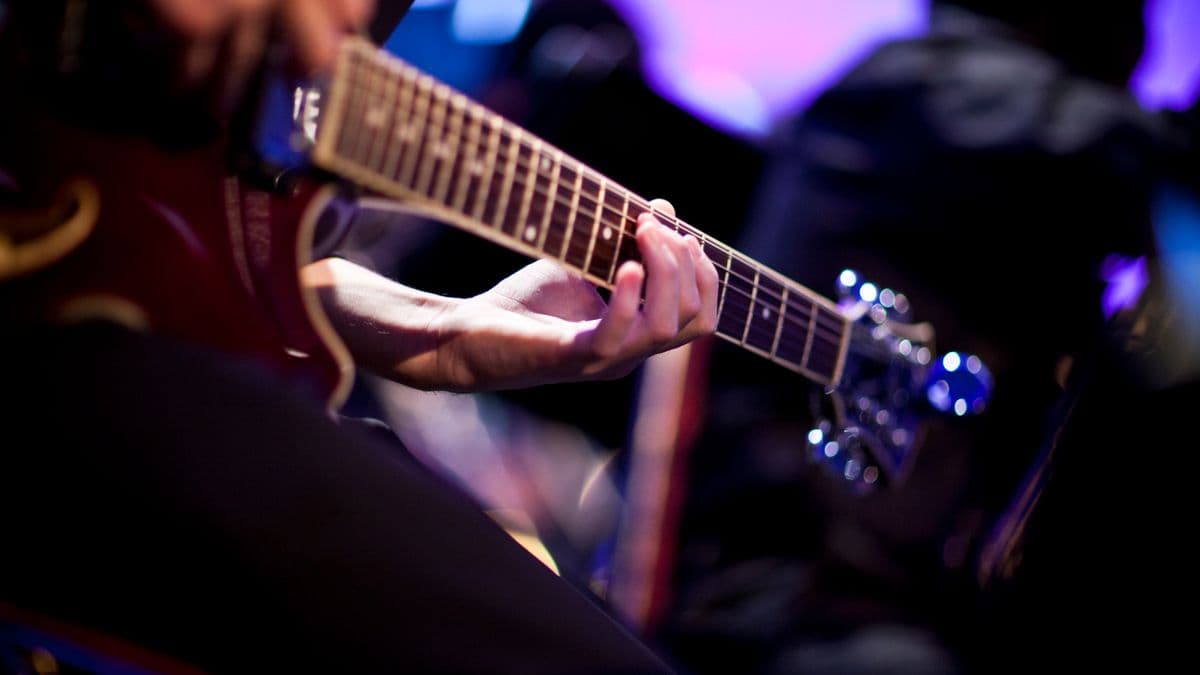 Close up of a musicians hand playing a guitar.