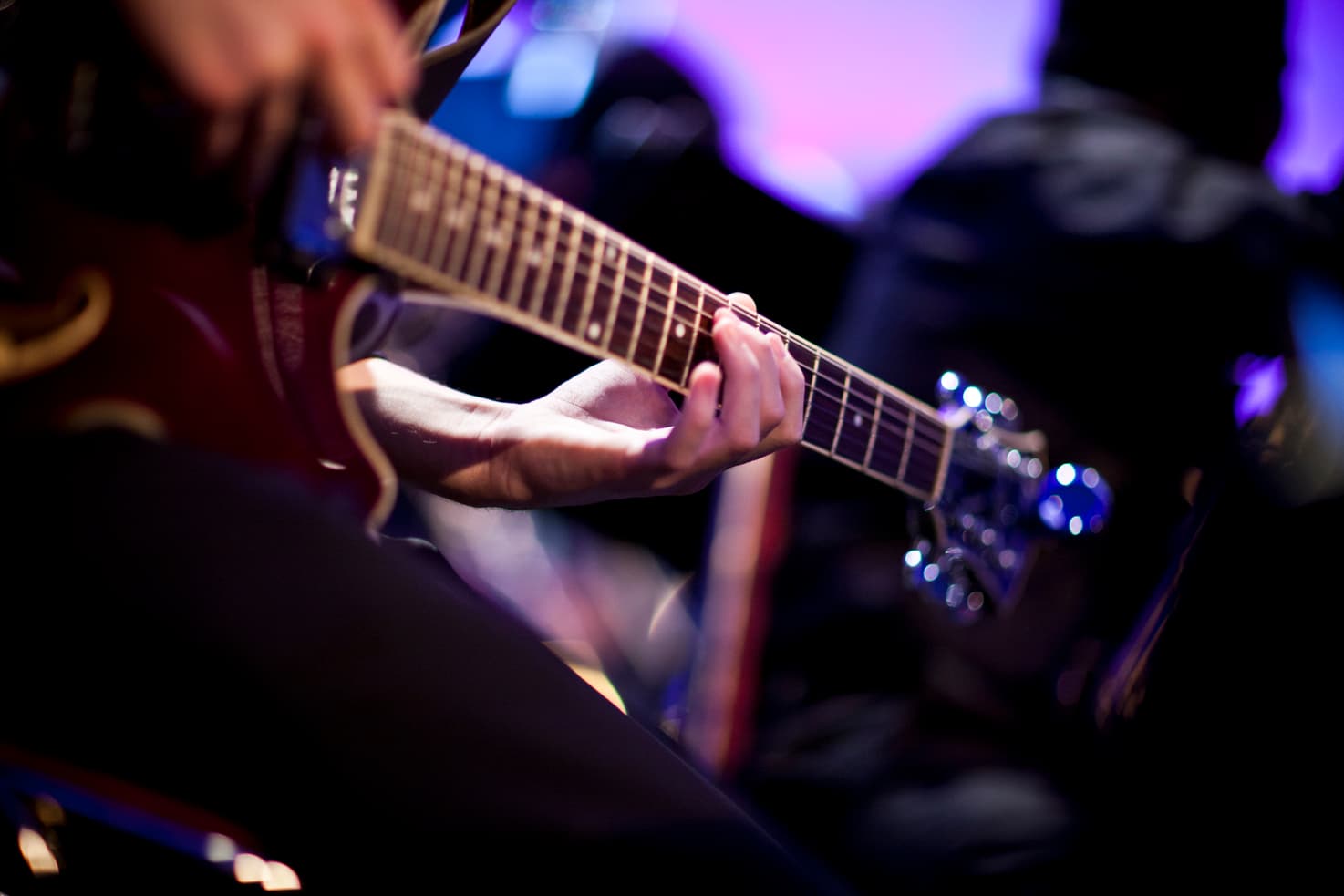 Close up of a musicians hand playing a guitar.