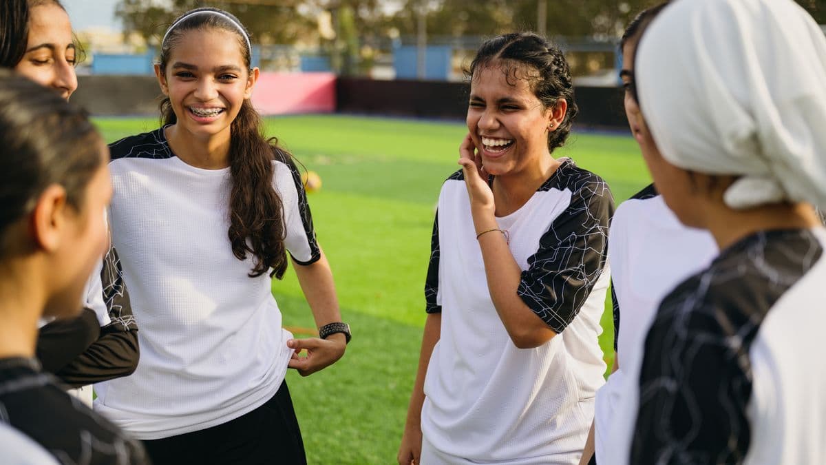 Cheerful soccer players talking at sports field.