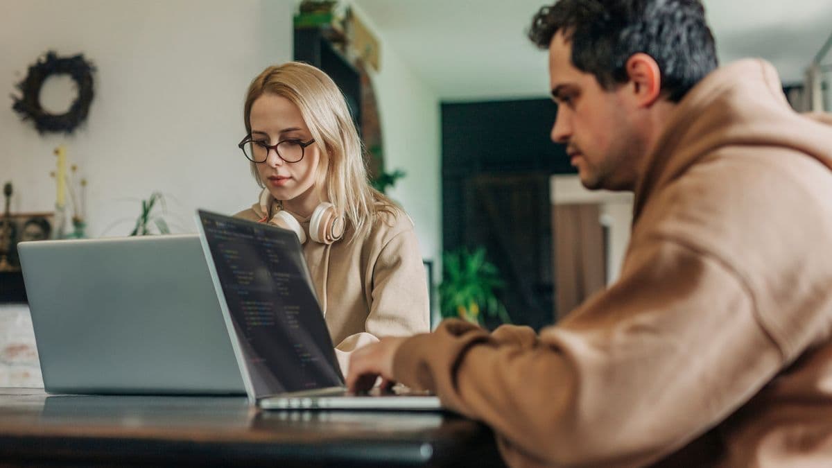Two people sat at a table working on their laptops.