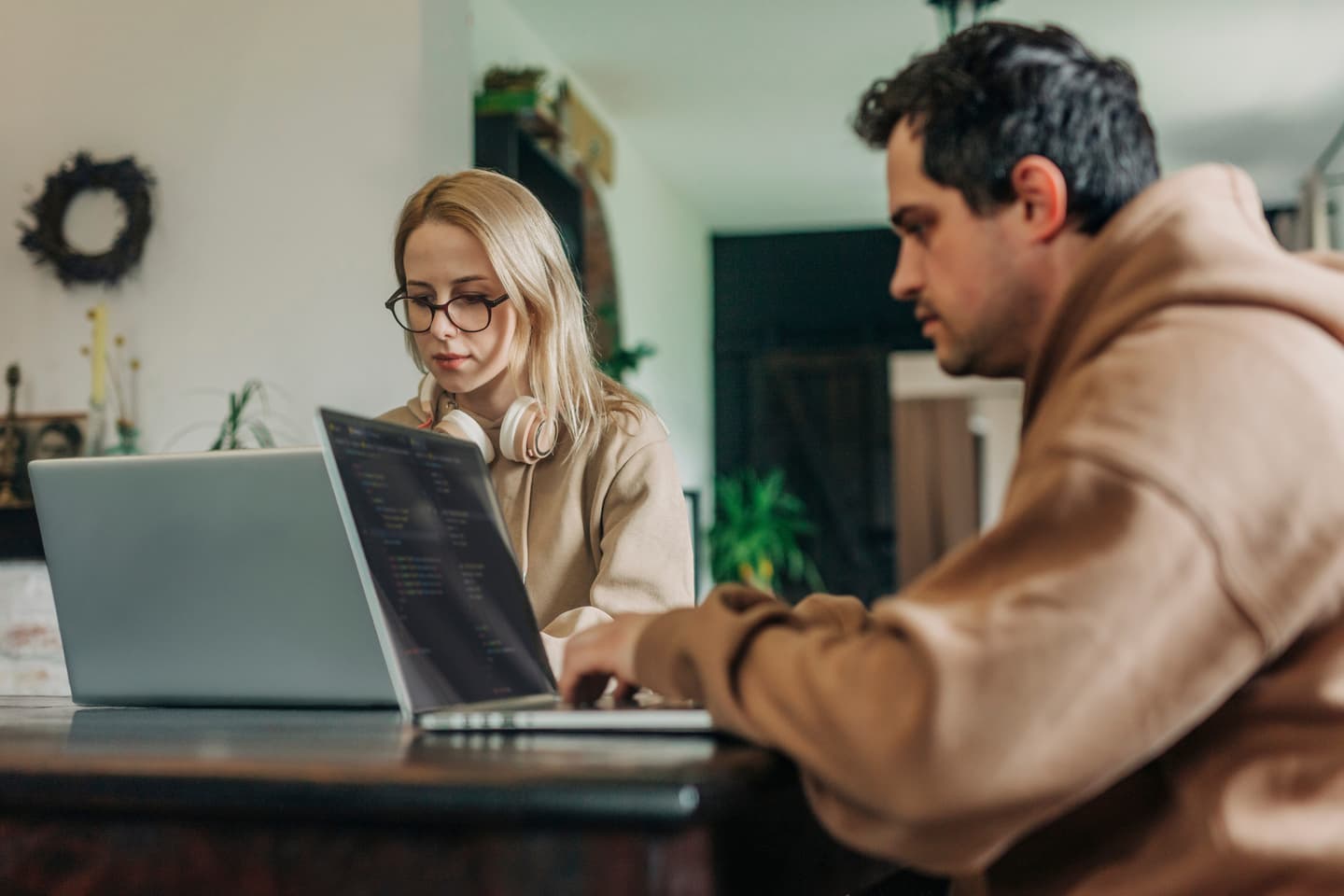 Two people sat at a table working on their laptops.
