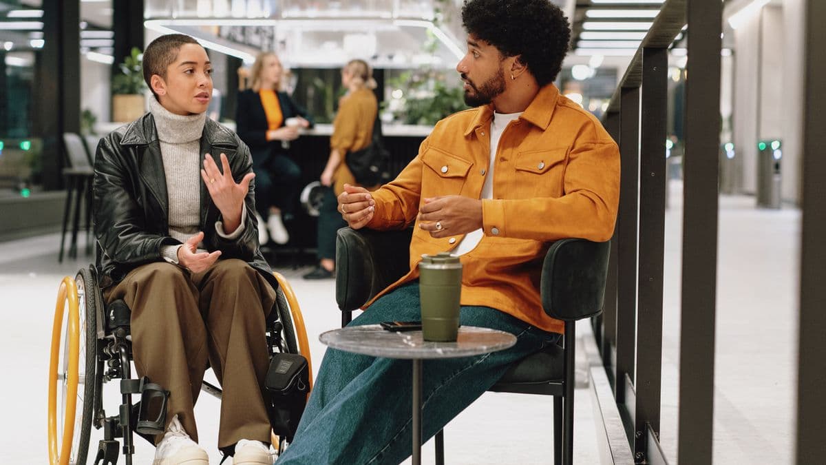 Two colleagues have animated chat in lobby area of modern office