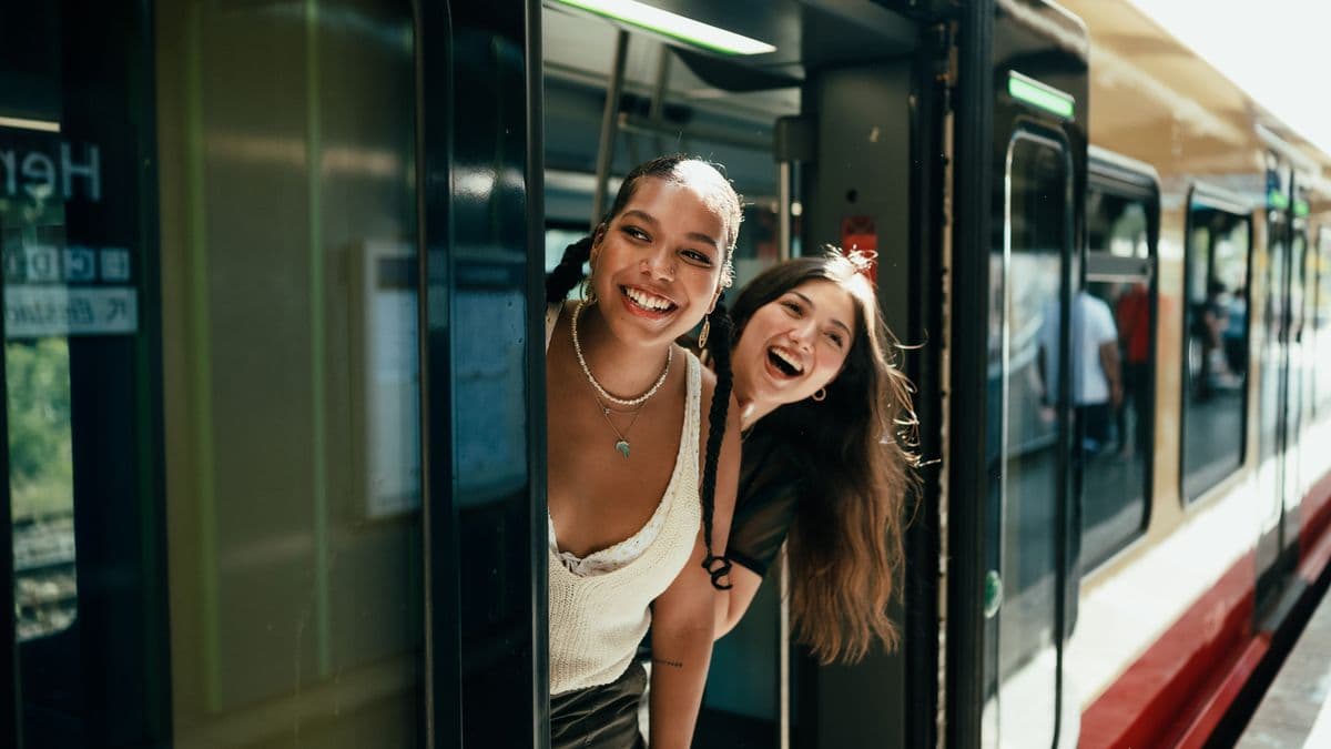 Young women smiling and looking out of an open train door.